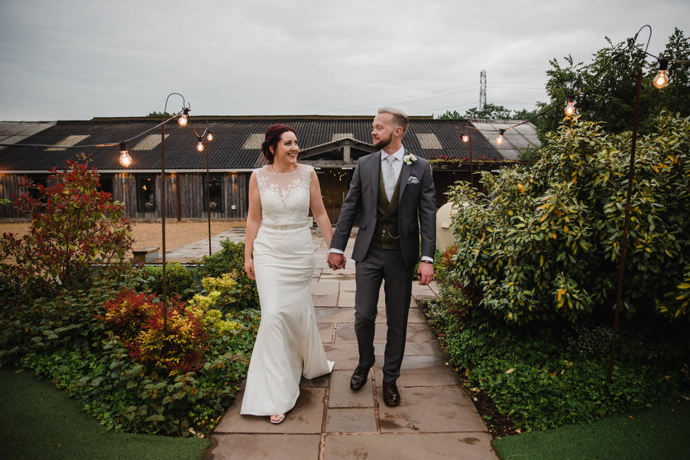 newlyweds walking towards camera at the entrance of Owen House Wedding Barn