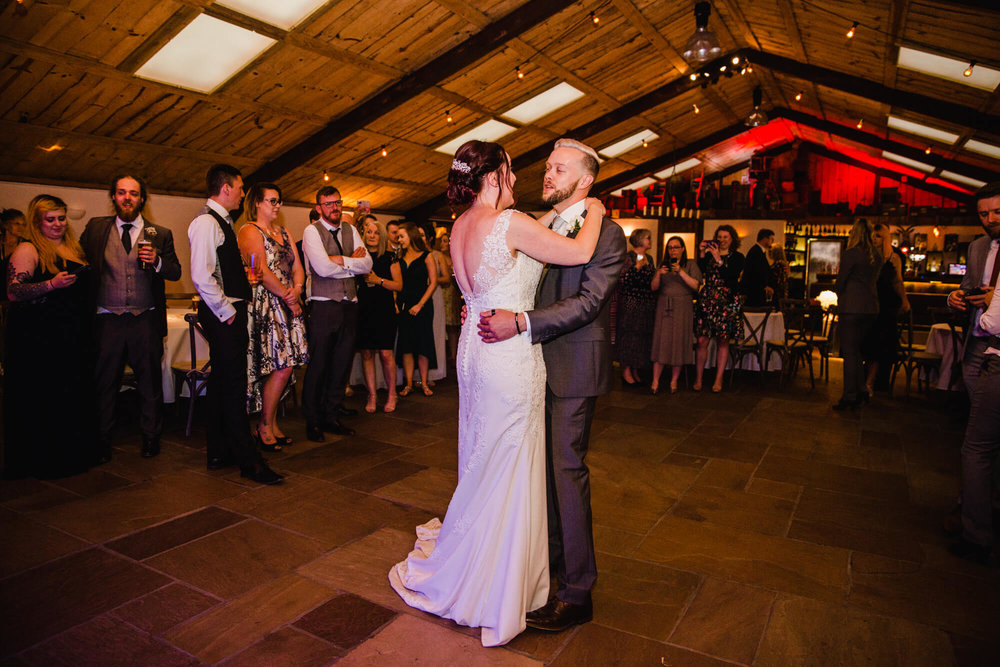 newlyweds sharing first dance with wedding guests looking on