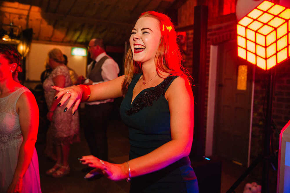 maid of honour dancing and laughing at end of evening in a high contrast colourful photograph