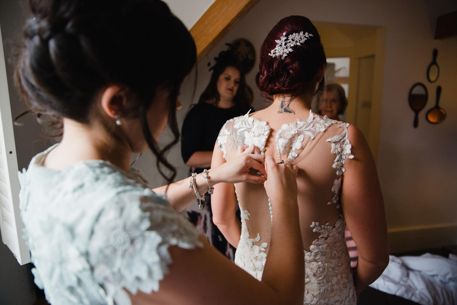 close up detail photograph of bridesmaid fastening wedding gown