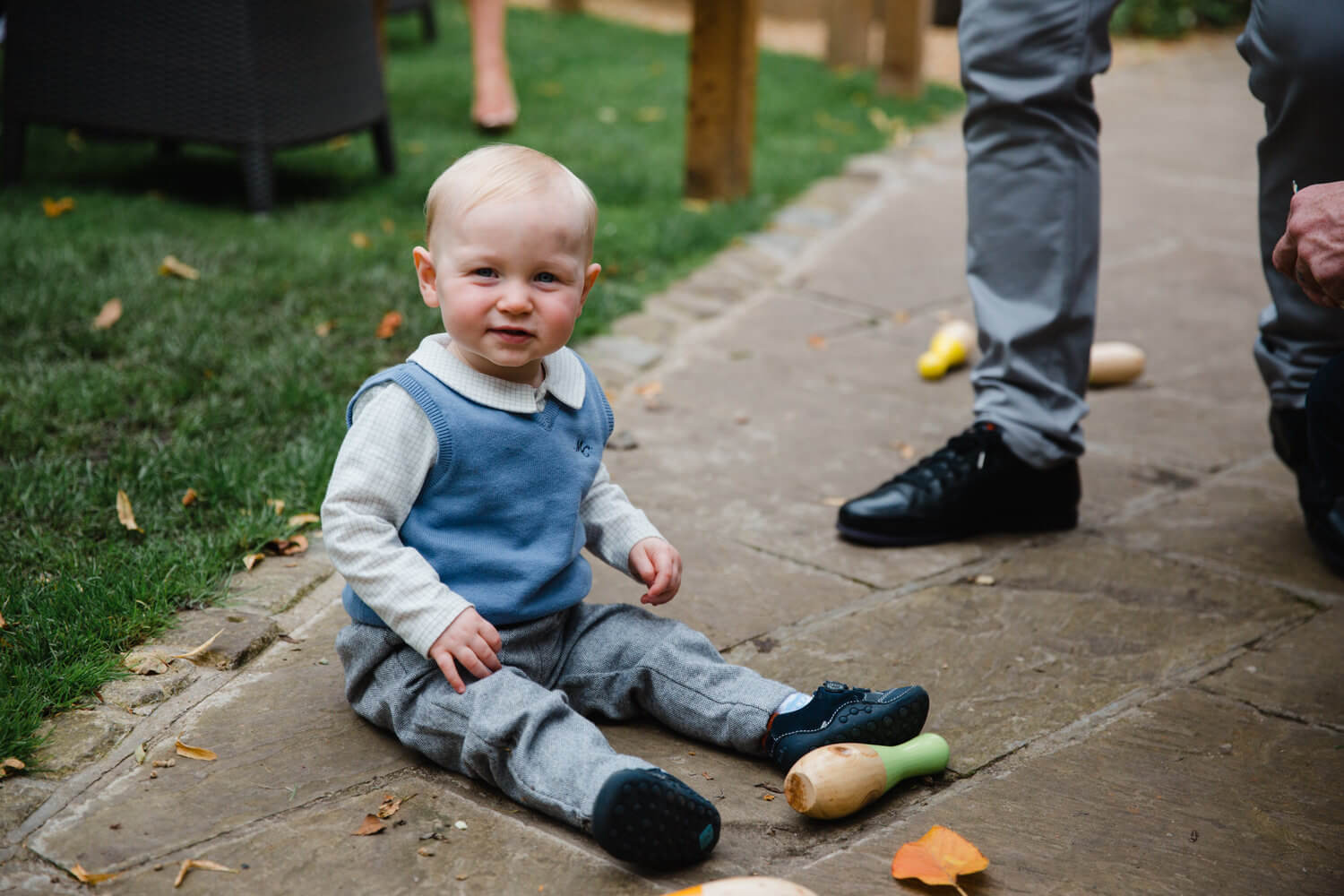 page boy sat on floor looking at camera while playing skittles lawn game