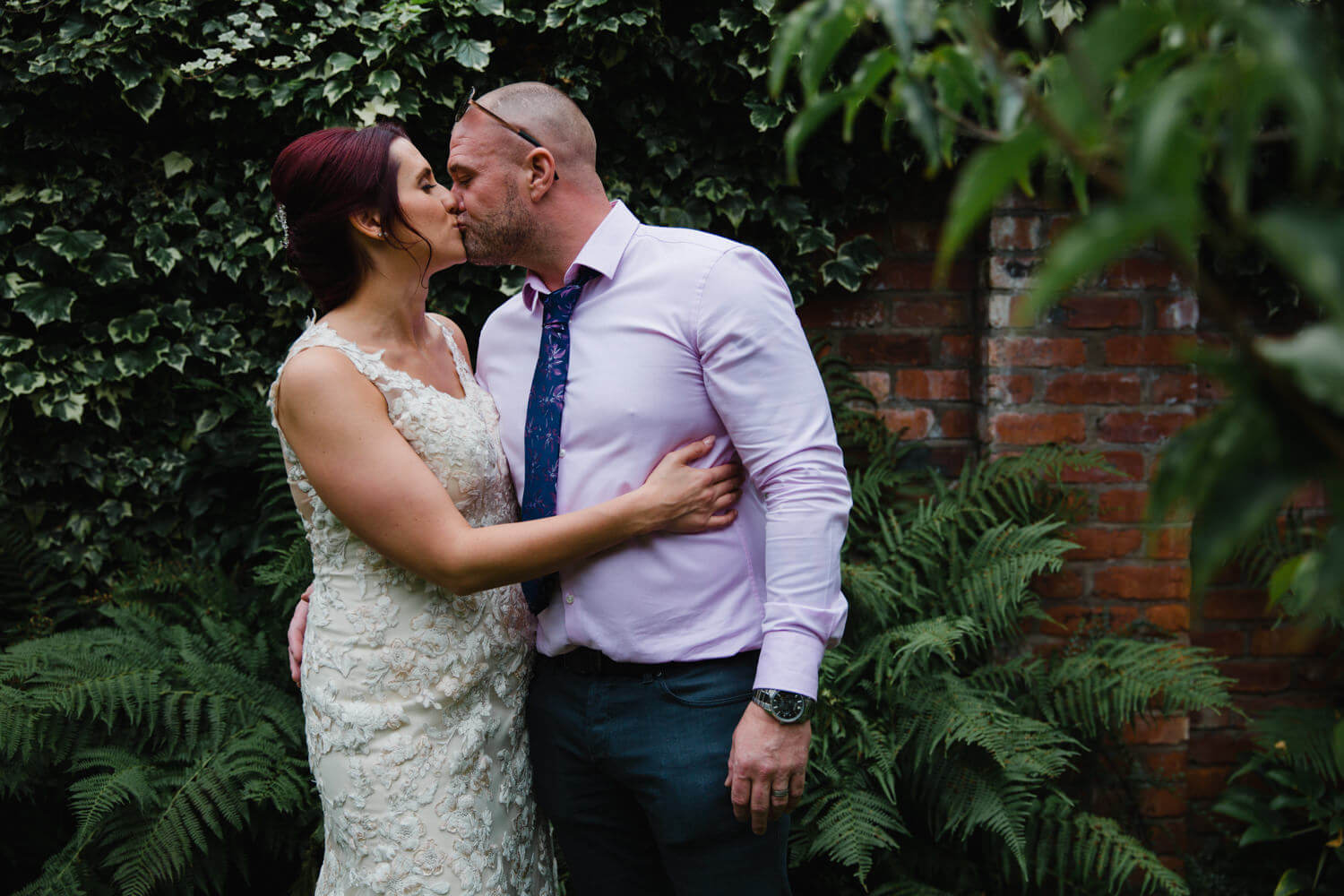 landscape portrait of bride and groom kissing in gardens of Eleven Didsbury Park