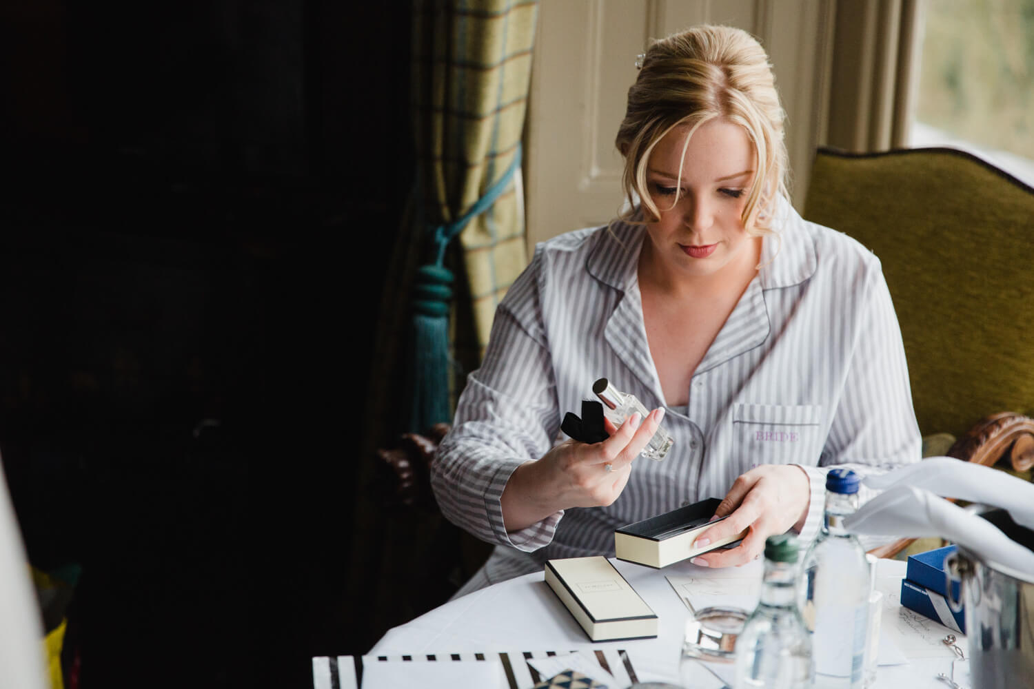 bride sat at bridal suite table doing make up