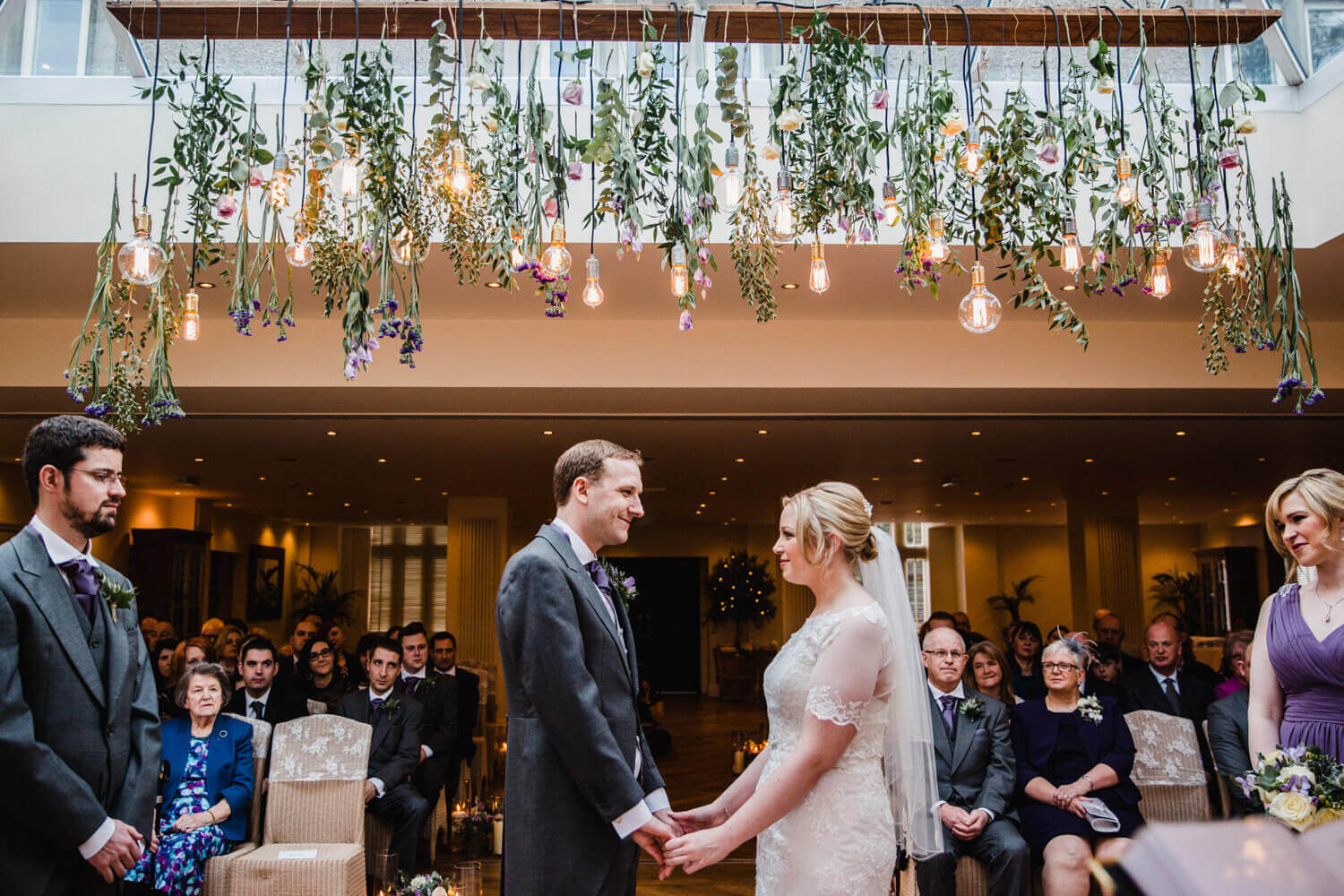 Bride and groom exchanging vows and nuptials while bridal party look on