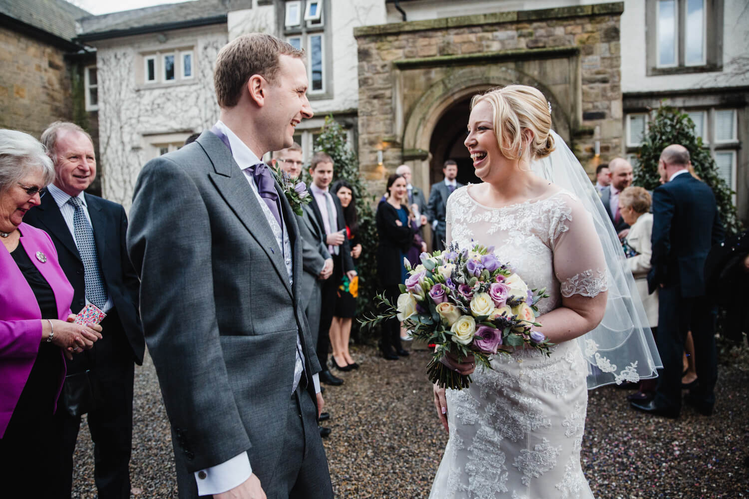 newly married couple laughing at each other while full of confetti