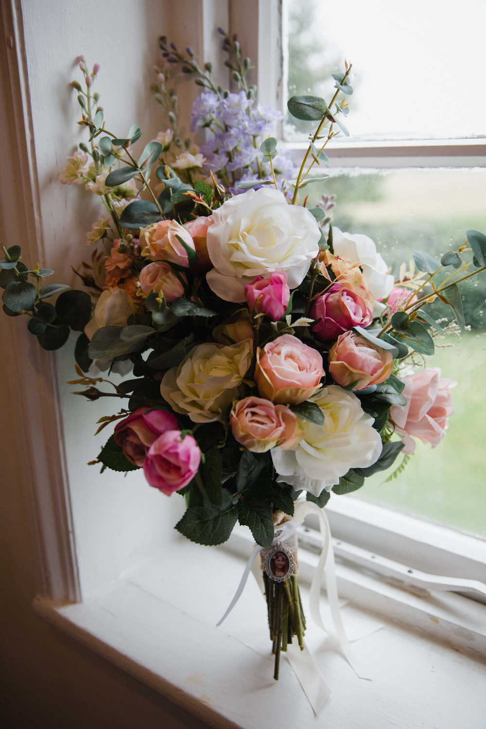 bouquet of flowers resting upright in window as natural light shines in