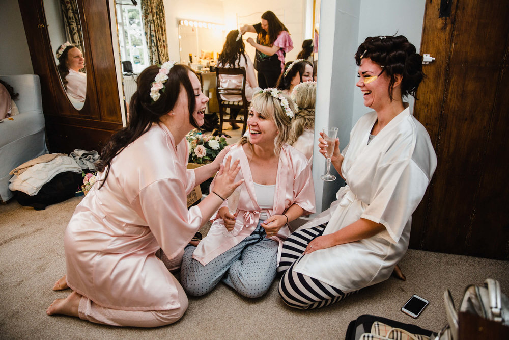 bridesmaids sharing laugh and joke with bride in mirror of bridal suite