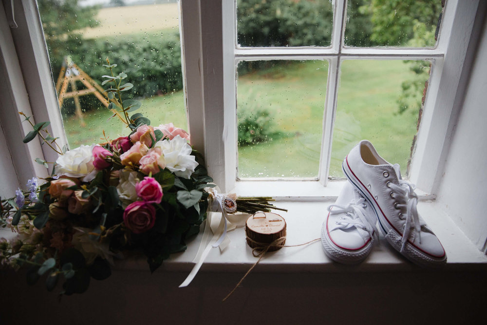 bouquet and converse wedding shoes sitting on window ledge overlooking garden at stock farm