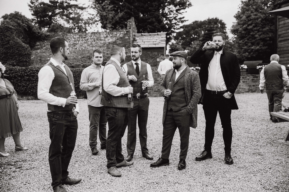 black and white monochrome photograph of groomsmen in tweed waiting for ceremony