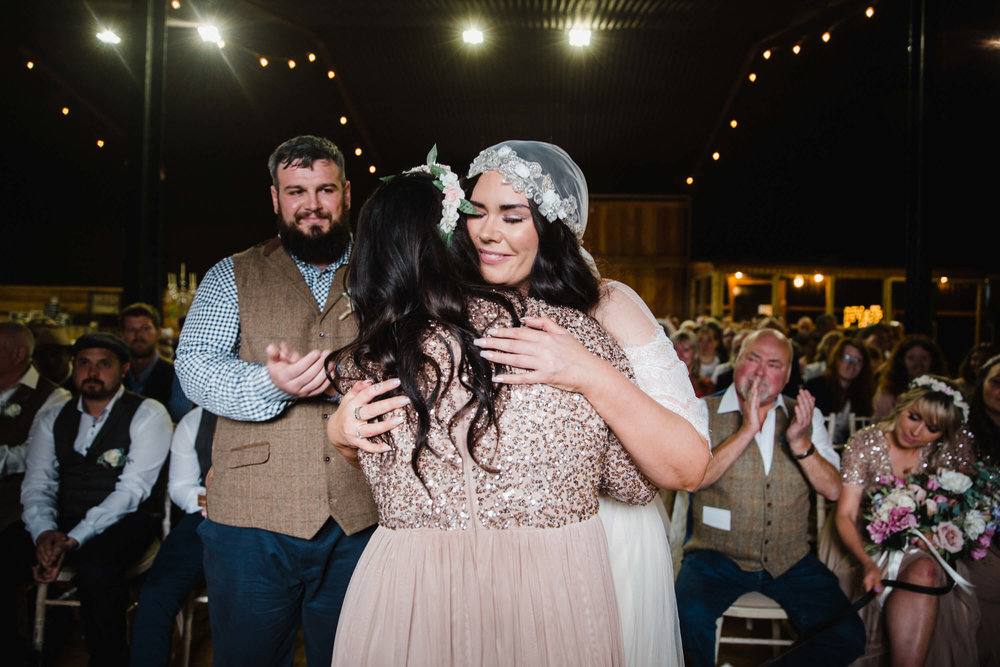 love is in large supply as bride shares hug with bridesmaid 