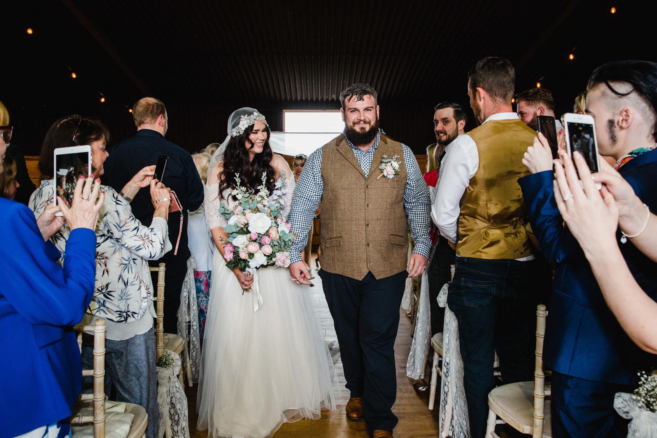 newly married couple walk down aisle for processional service