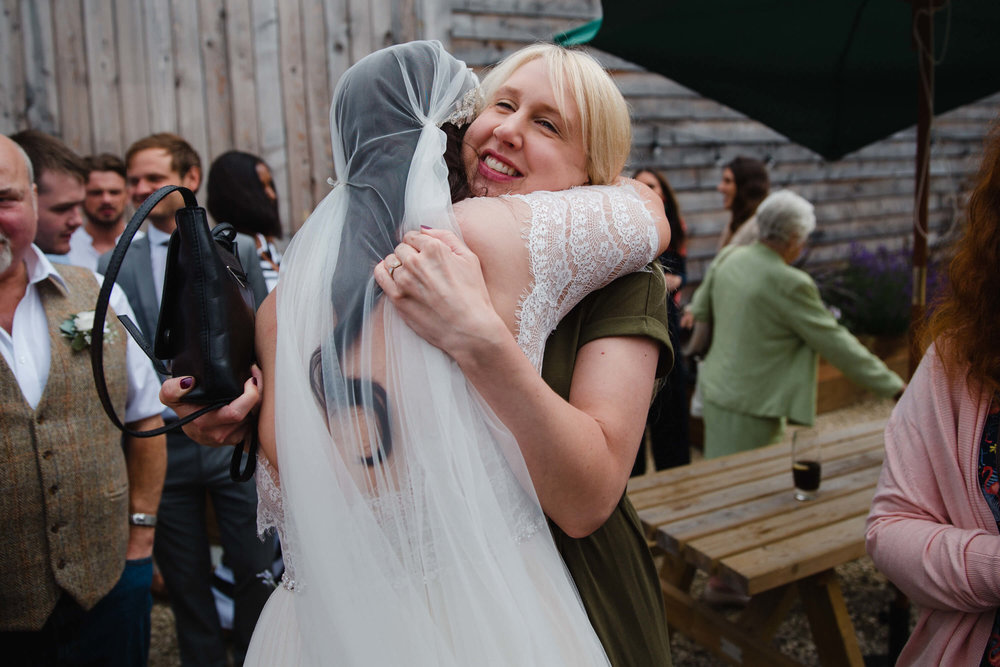 newly married bride shares intimate natural hug with guest