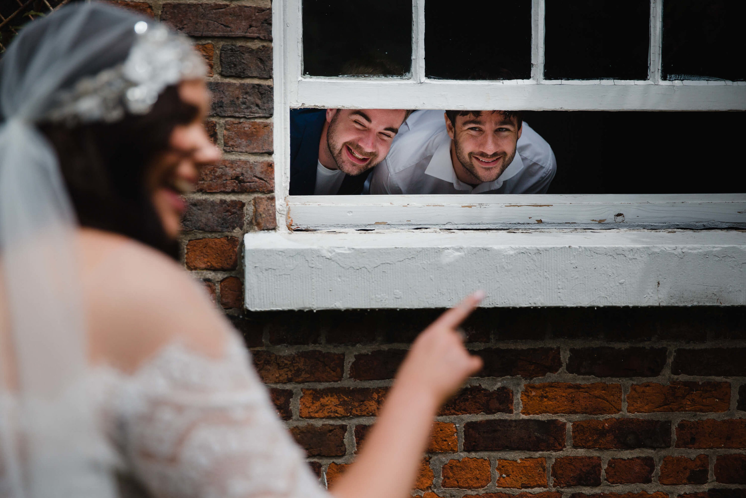 bride in foreground pointing at guests in window