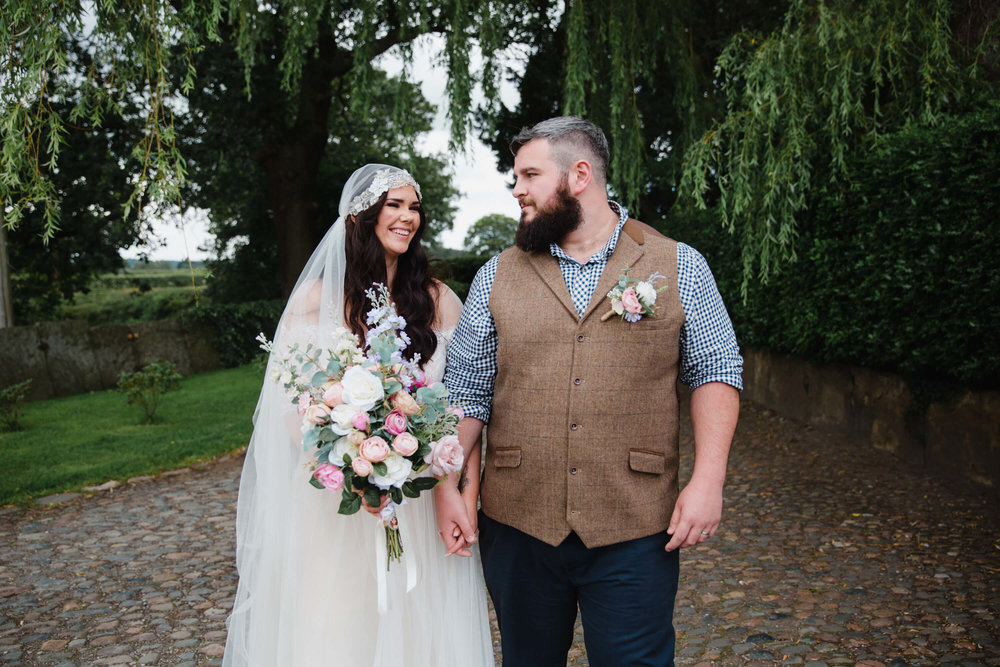 newlyweds take a stroll in cobbled orchard pathway