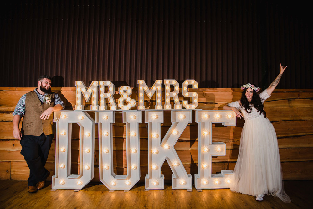 portrait of bride and groom with the word is love light up lettering