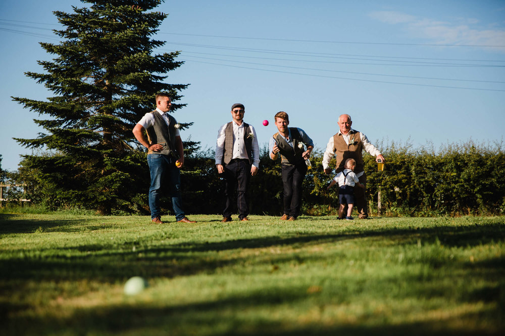 photograph of groomsmen playing lawn boules in pasture