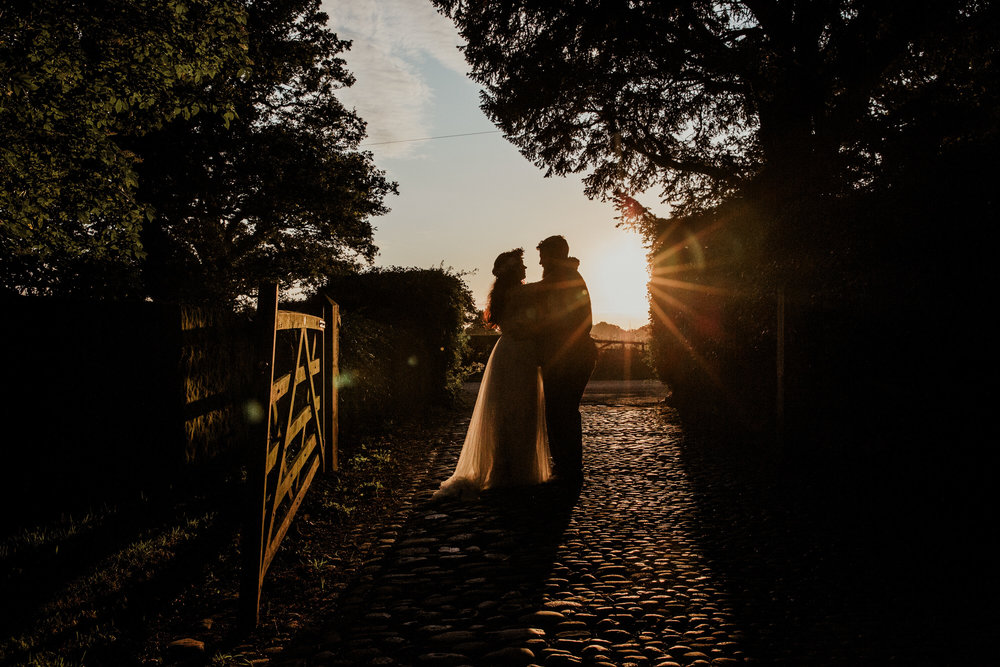 sunset portrait of bride and groom silhouette on cobbled path at Stock Farm wedding venue