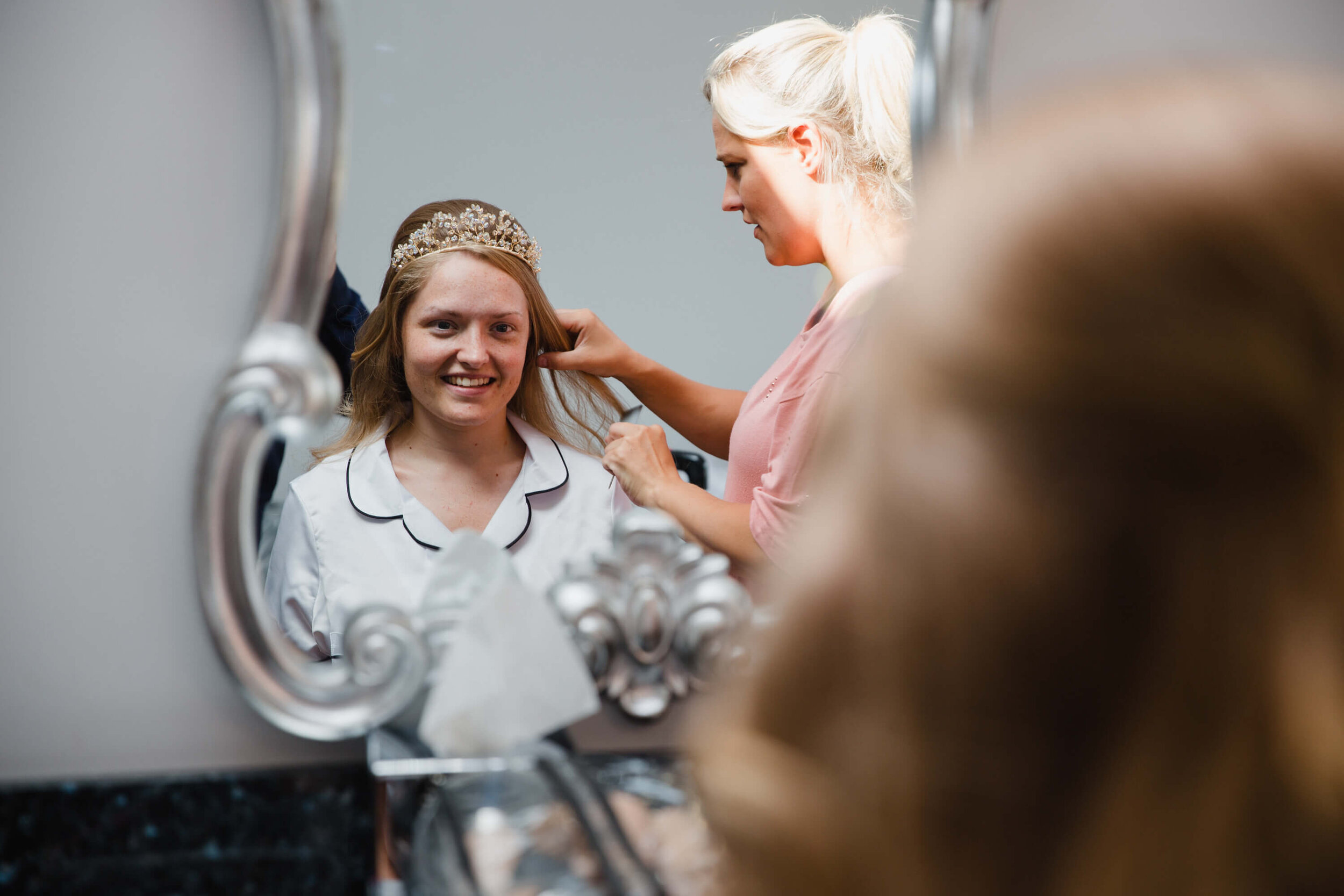 close up photograph of bride having hair styled in mirror