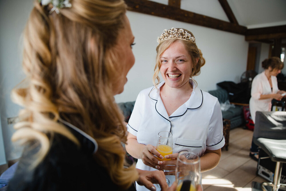 bride looking at camera while laughing with bridesmaid