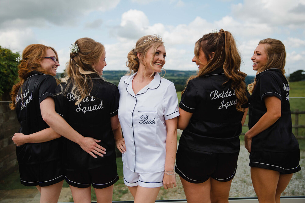 bride shares portrait with bridesmaids on porch of heaton residence