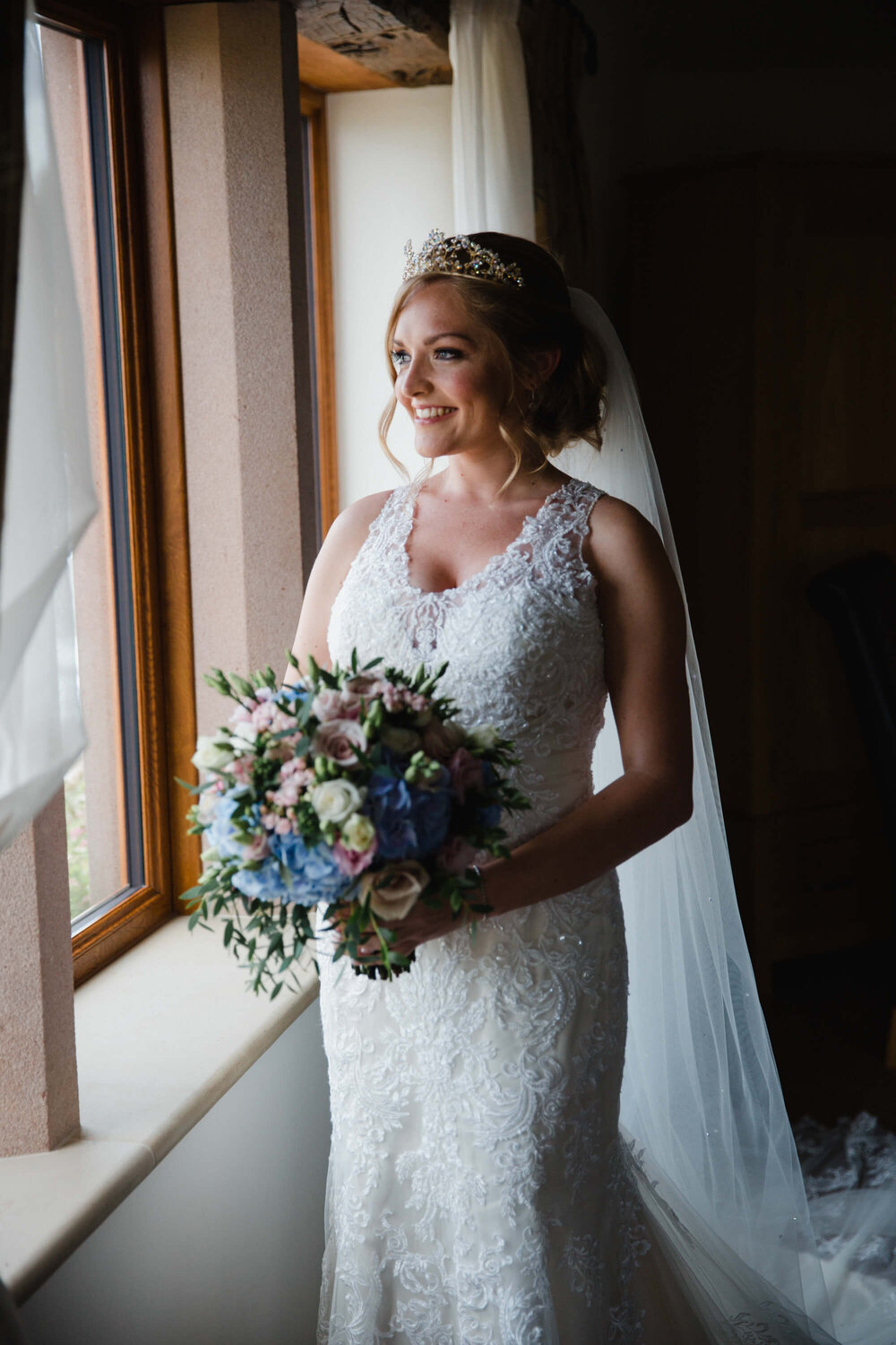 bride holding bouquet for portrait in window