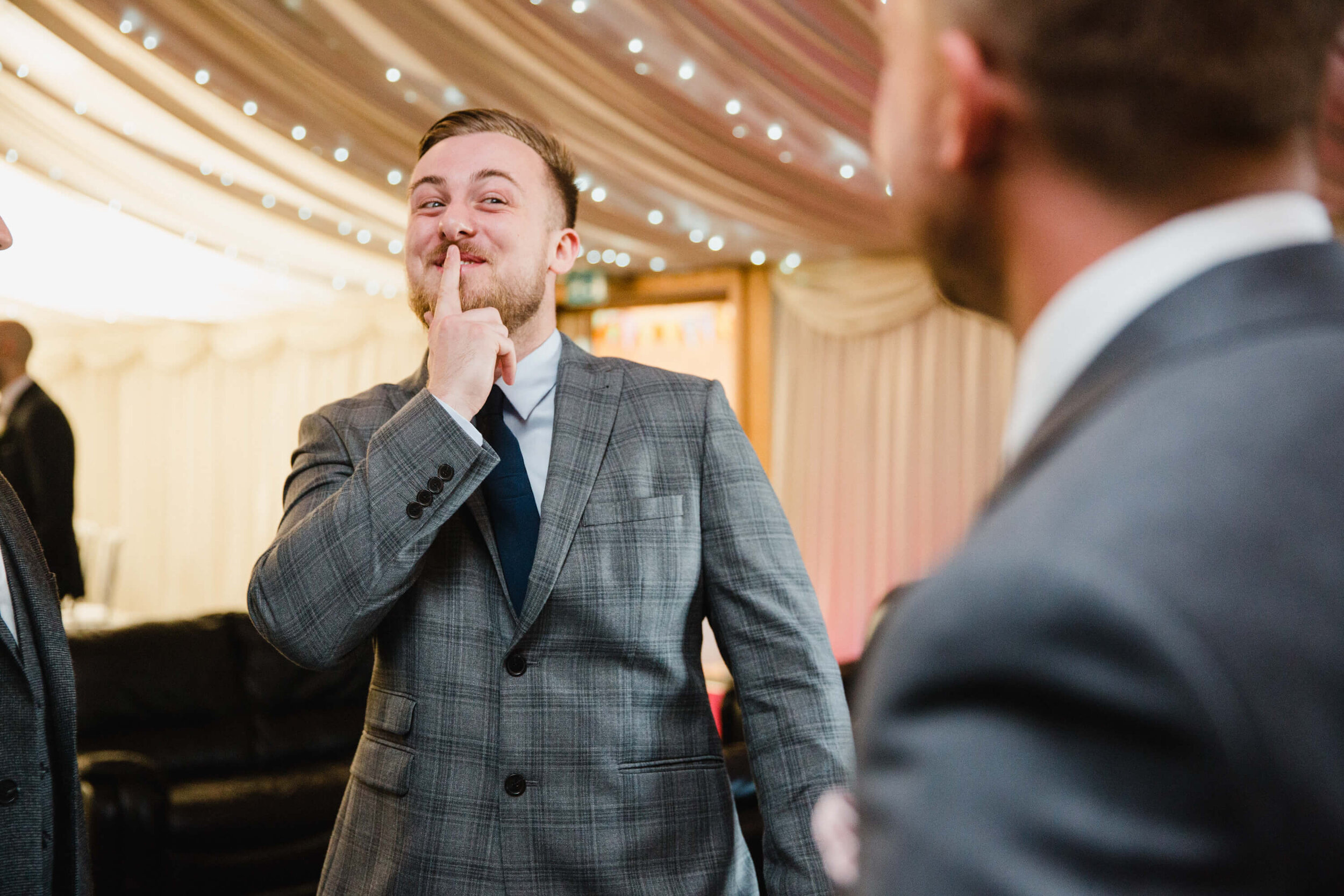 best man with finger over lips in candid moment at heaton house farm