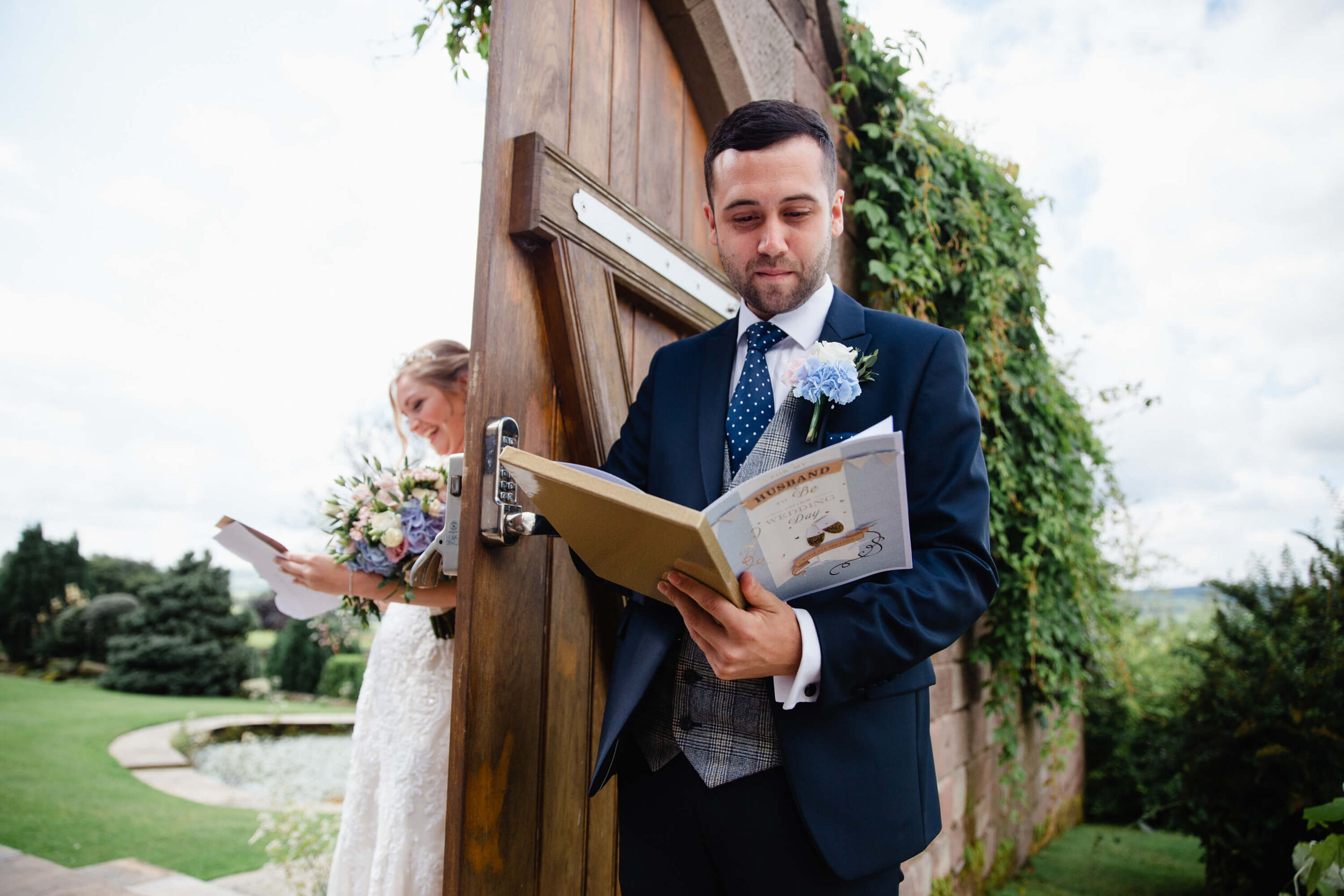 close up photograph of groom reading wedding card by the gateway of garden
