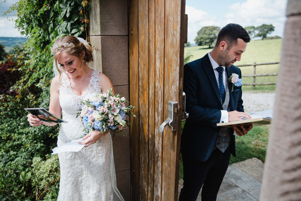 soon to be wedded couple reading cards moments before meadow wedding service