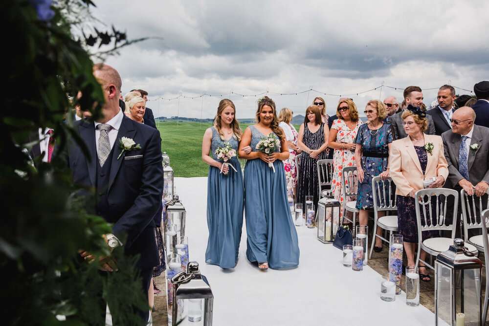 bridesmaids walking down aisle together for service processional to begin