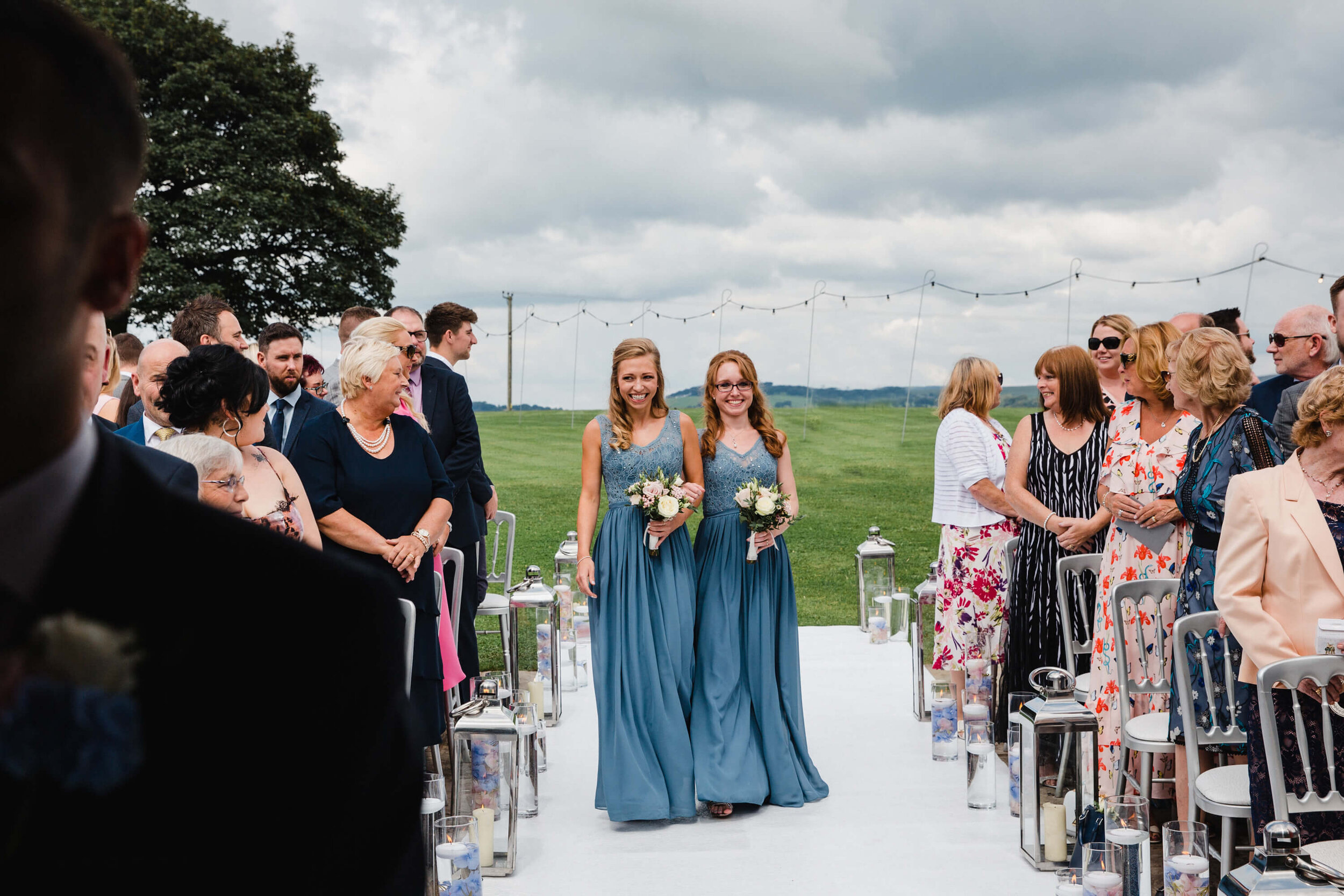 bridesmaids laughing and smiling while walking down aisle 