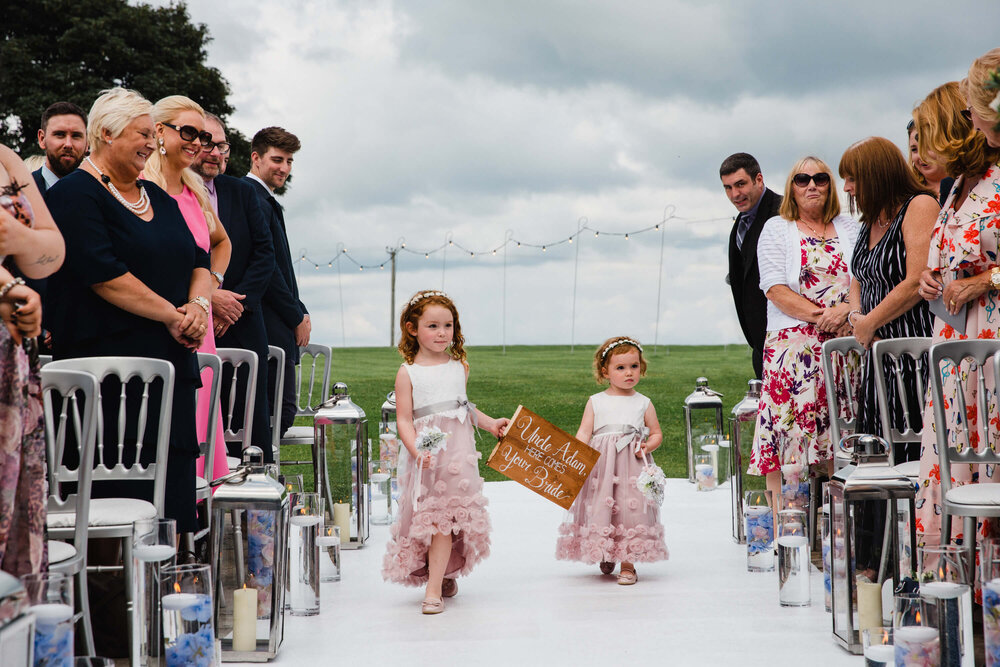 flower girls holding sign while walking down aisle