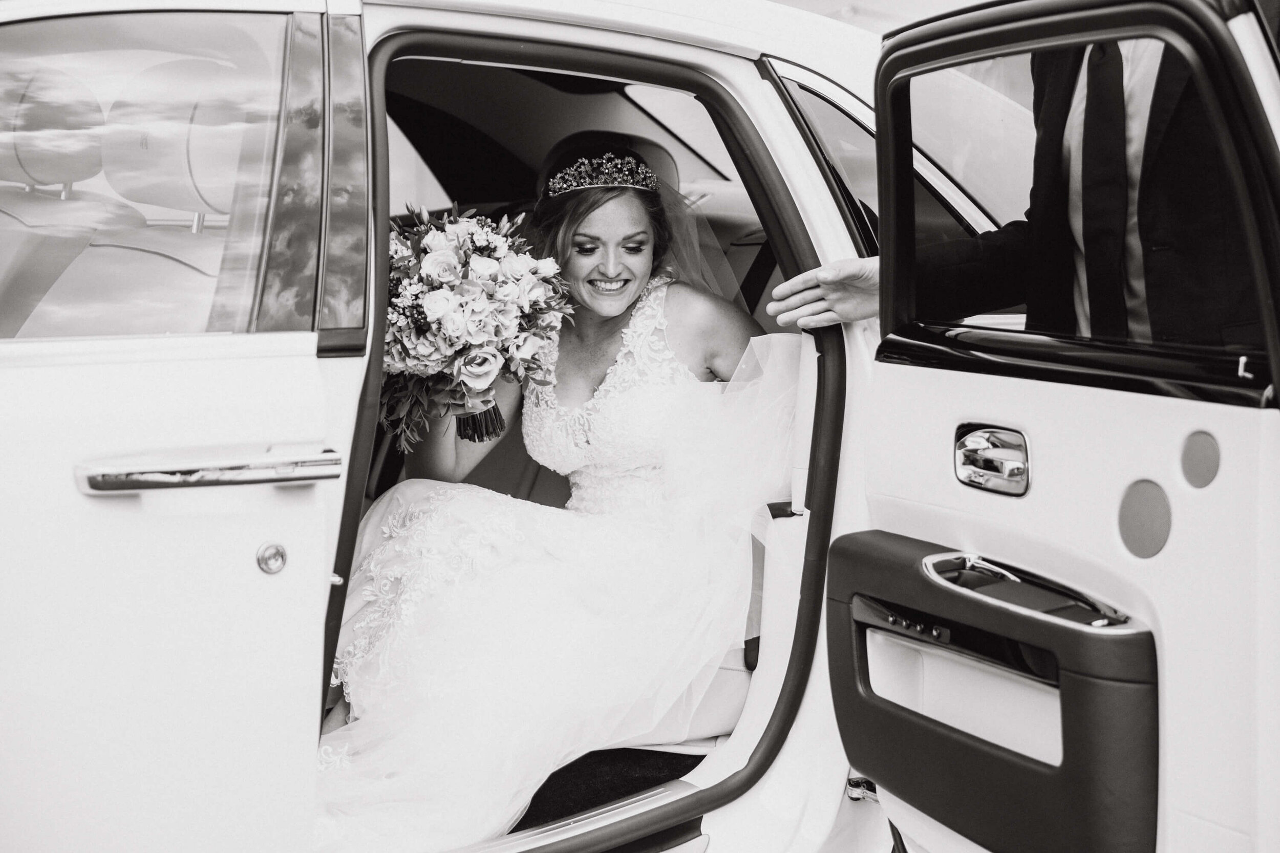 black and white photograph of bride exiting wedding car