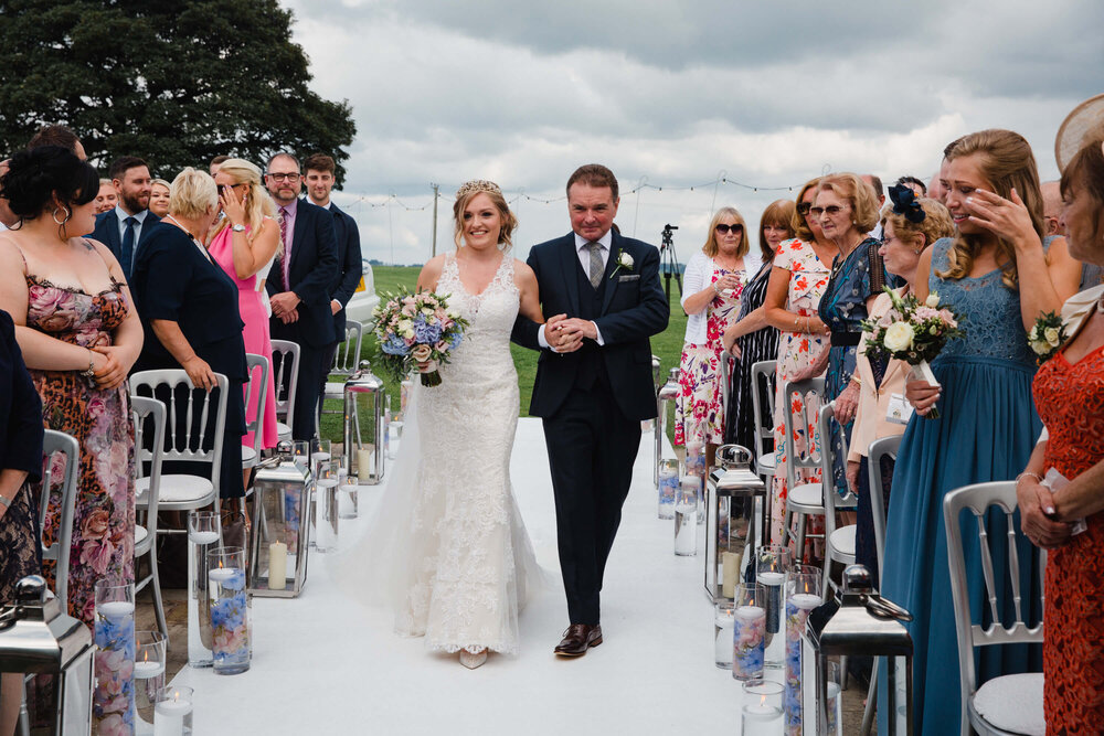 bride and father walking down aisle during rustic ceremony on homestead lawn