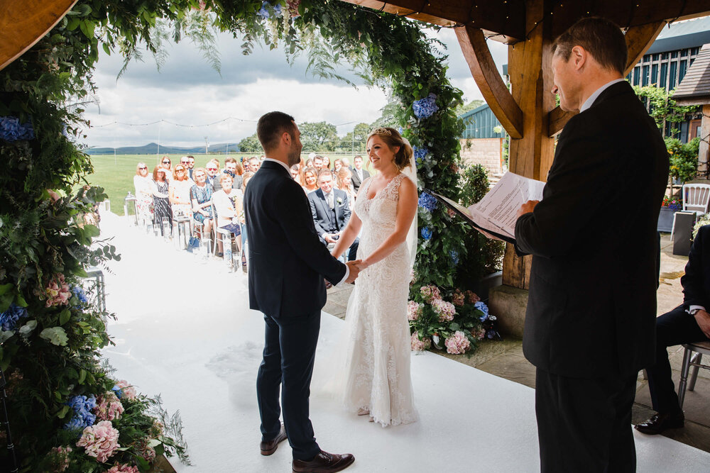wide angle lens photograph of bride holding hands with groom under quaint pagoda archway