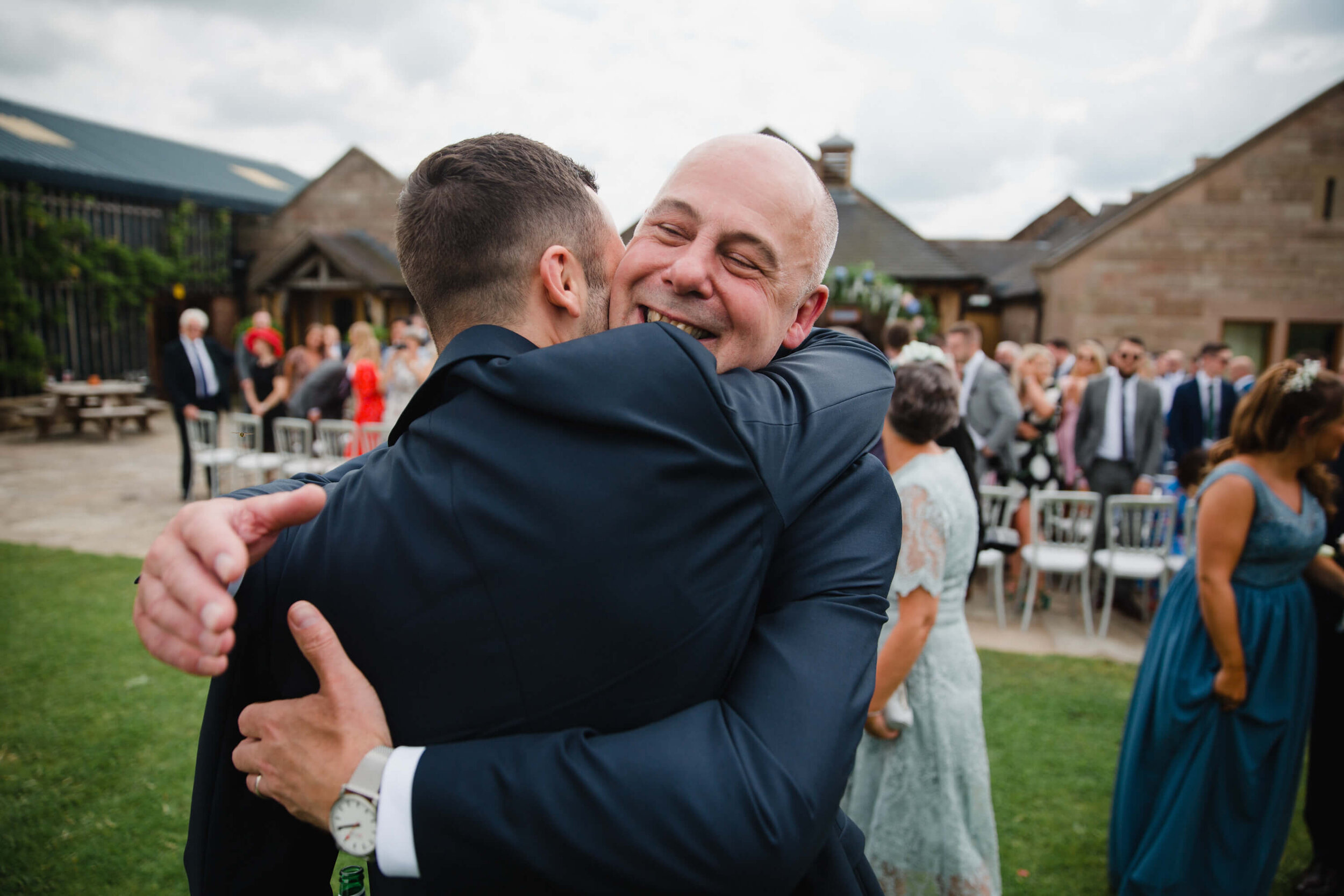 father of groom hugging son after service concludes