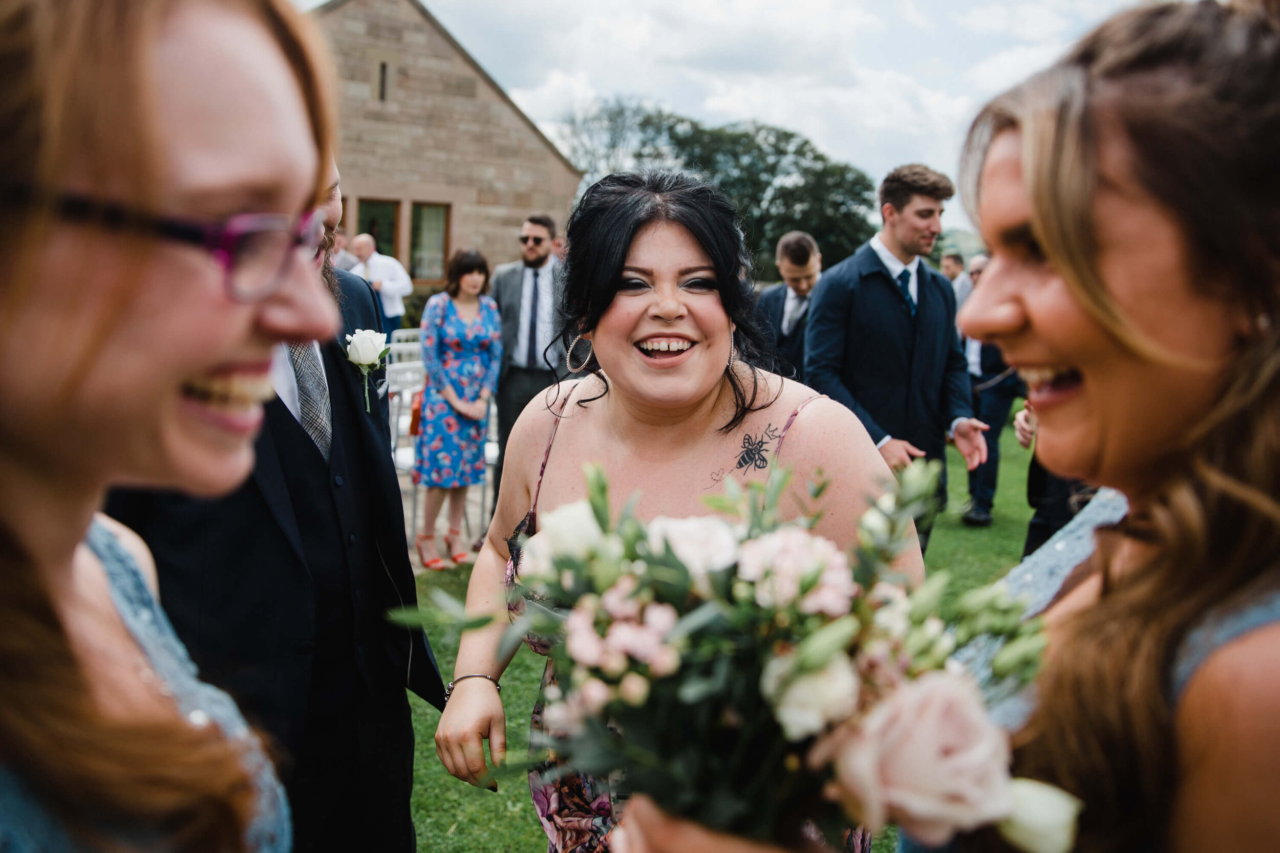 wedding guest sharing joke with bridesmaids on lawn