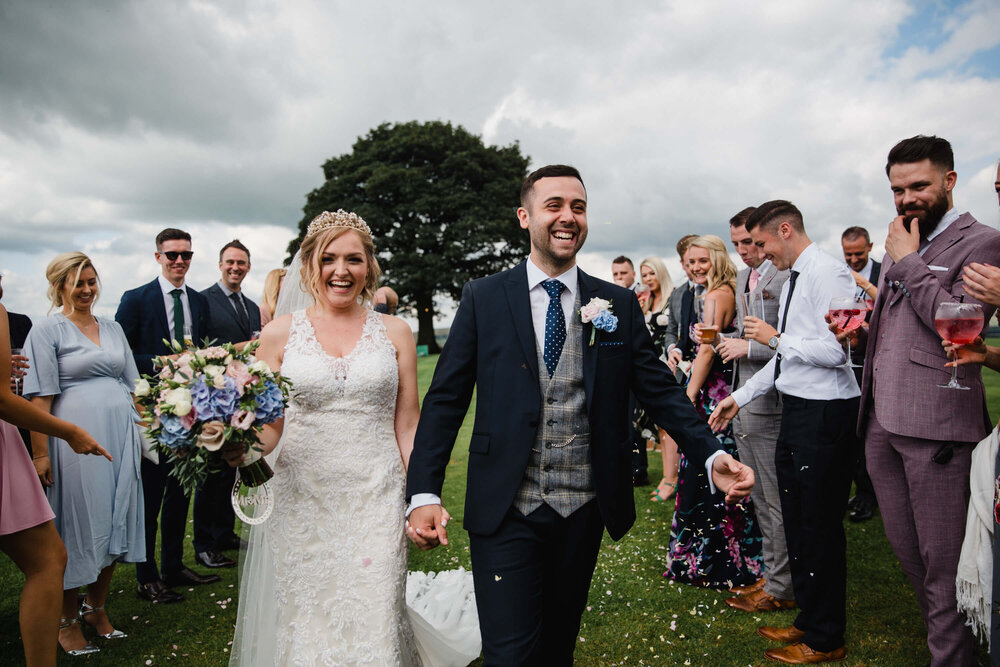 newlyweds celebrating with confetti on field at Heaton house farm