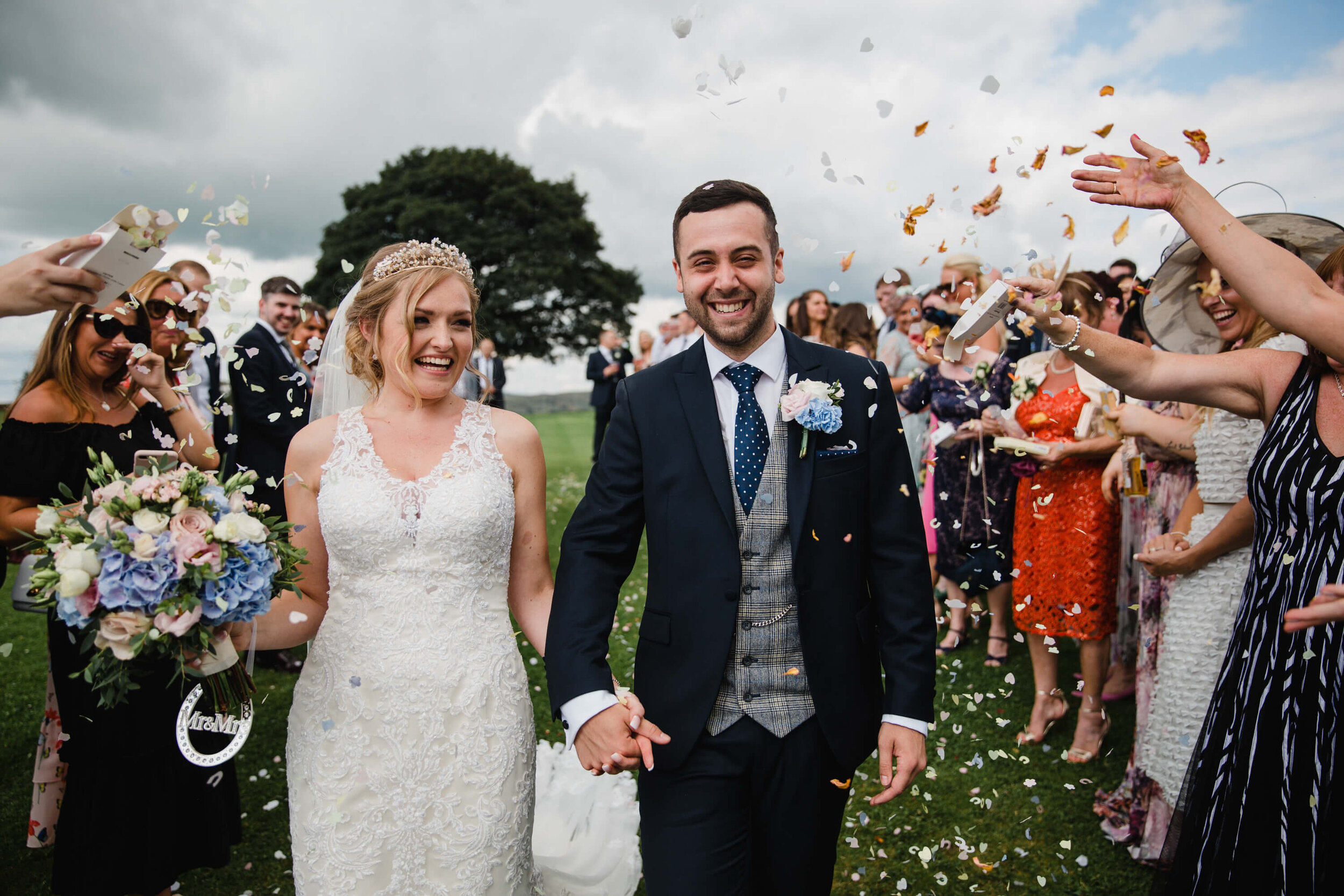 newly wedded couple having confetti thrown over them on field at Heaton house farm