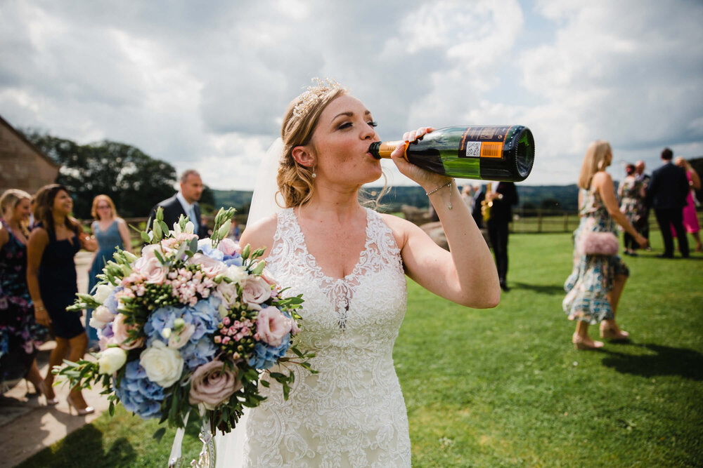 bride drinks bottle of champagne to celebrate marriage