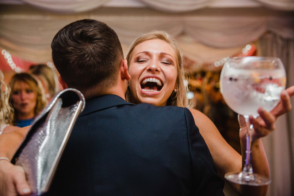 candid moment as guest exchanges hug with groom