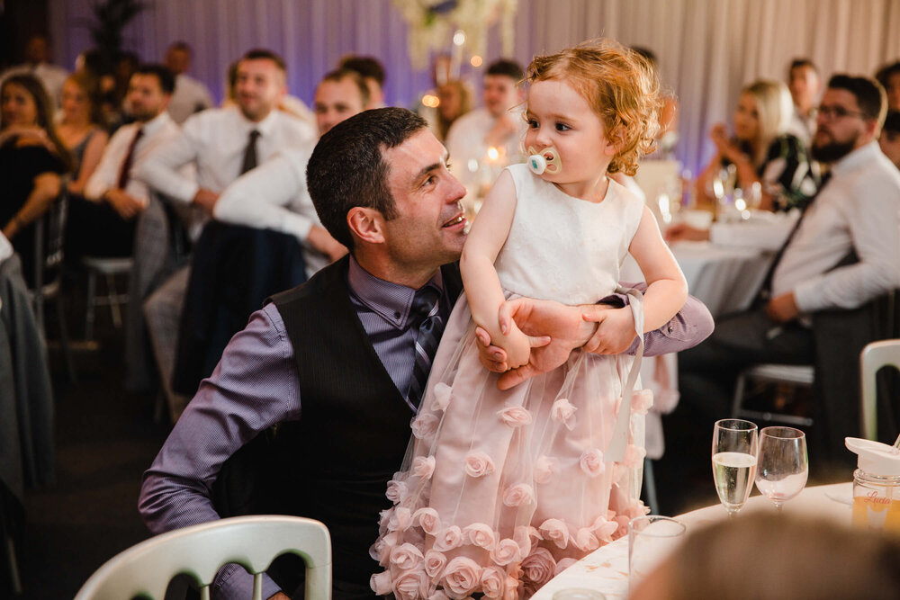 flower girl stood on fathers lap during speeches