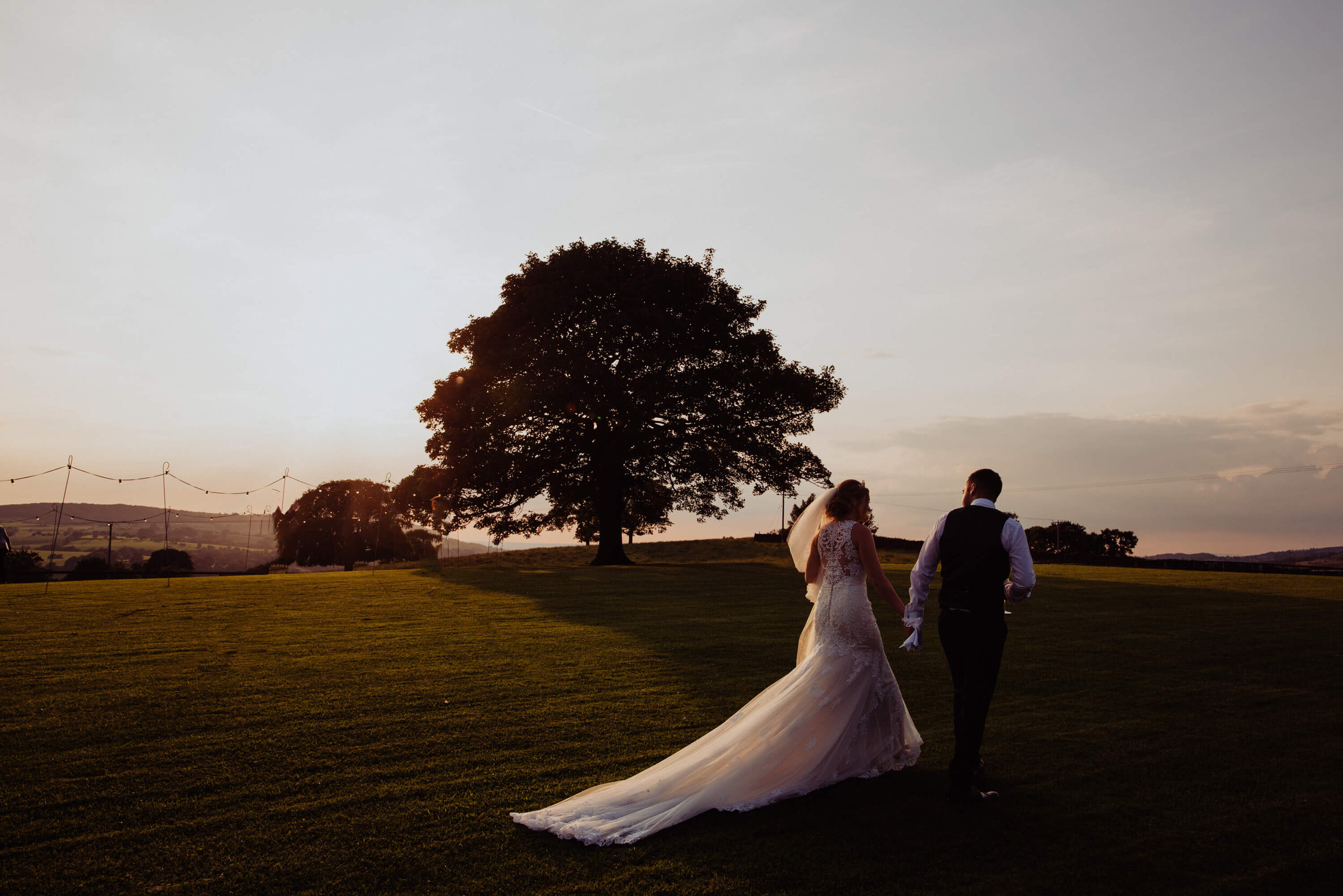 low exposure portrait of bride and groom walking together at sunset
