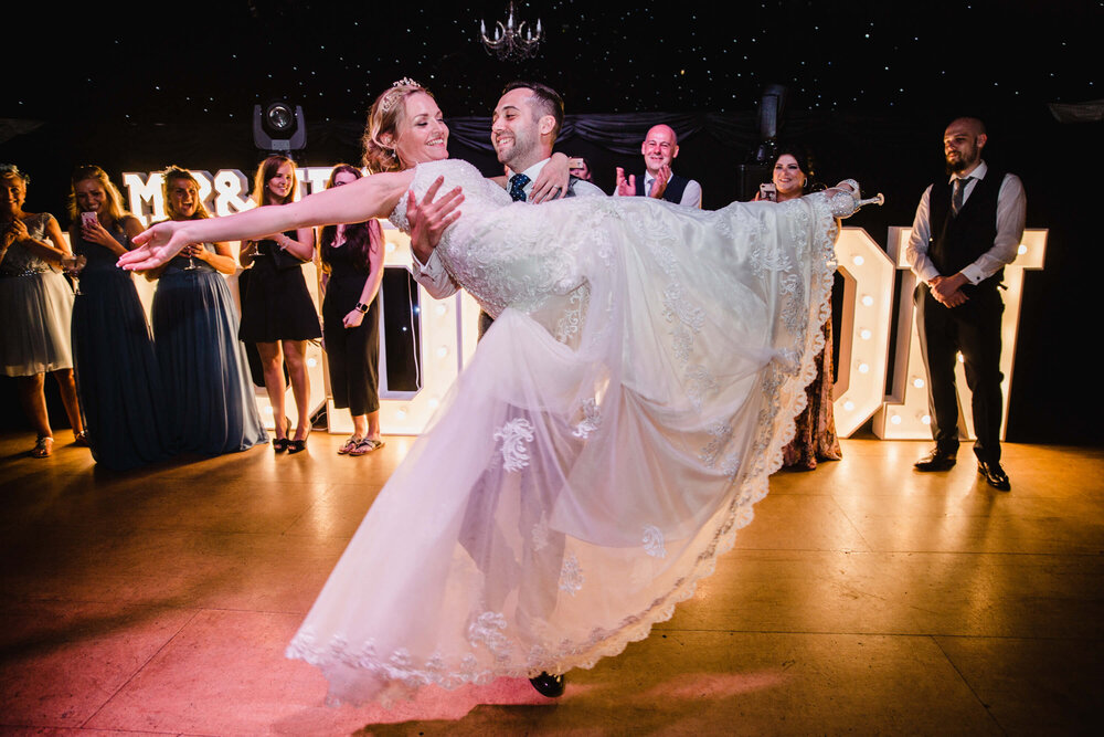 newlyweds dancing on floor together surrounded by friends and family