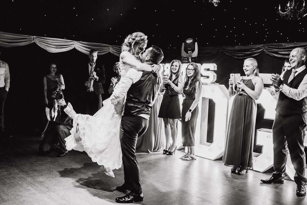 monochrome portrait of groom dancing with bride on barn dance floor at Heaton House