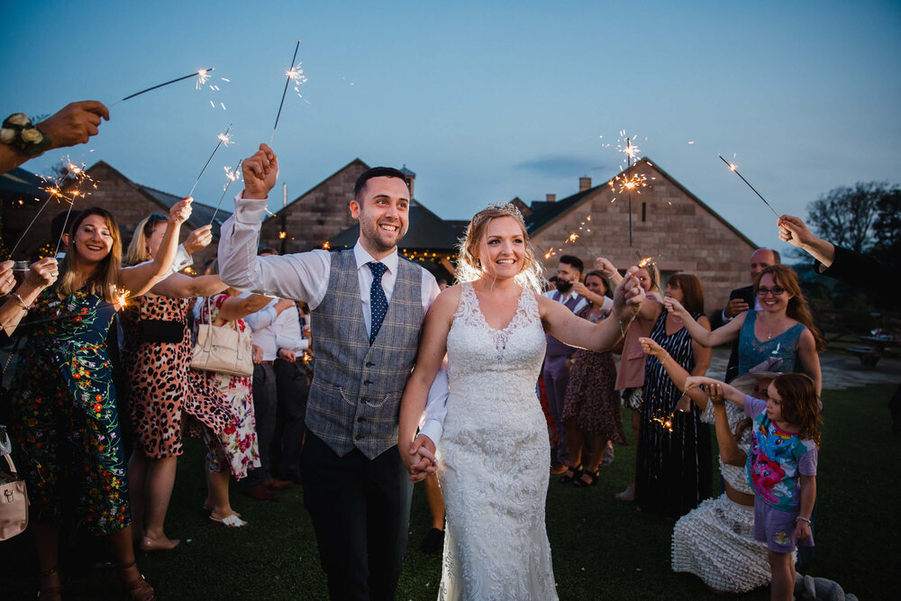 newly wedded couple walking between bridal party