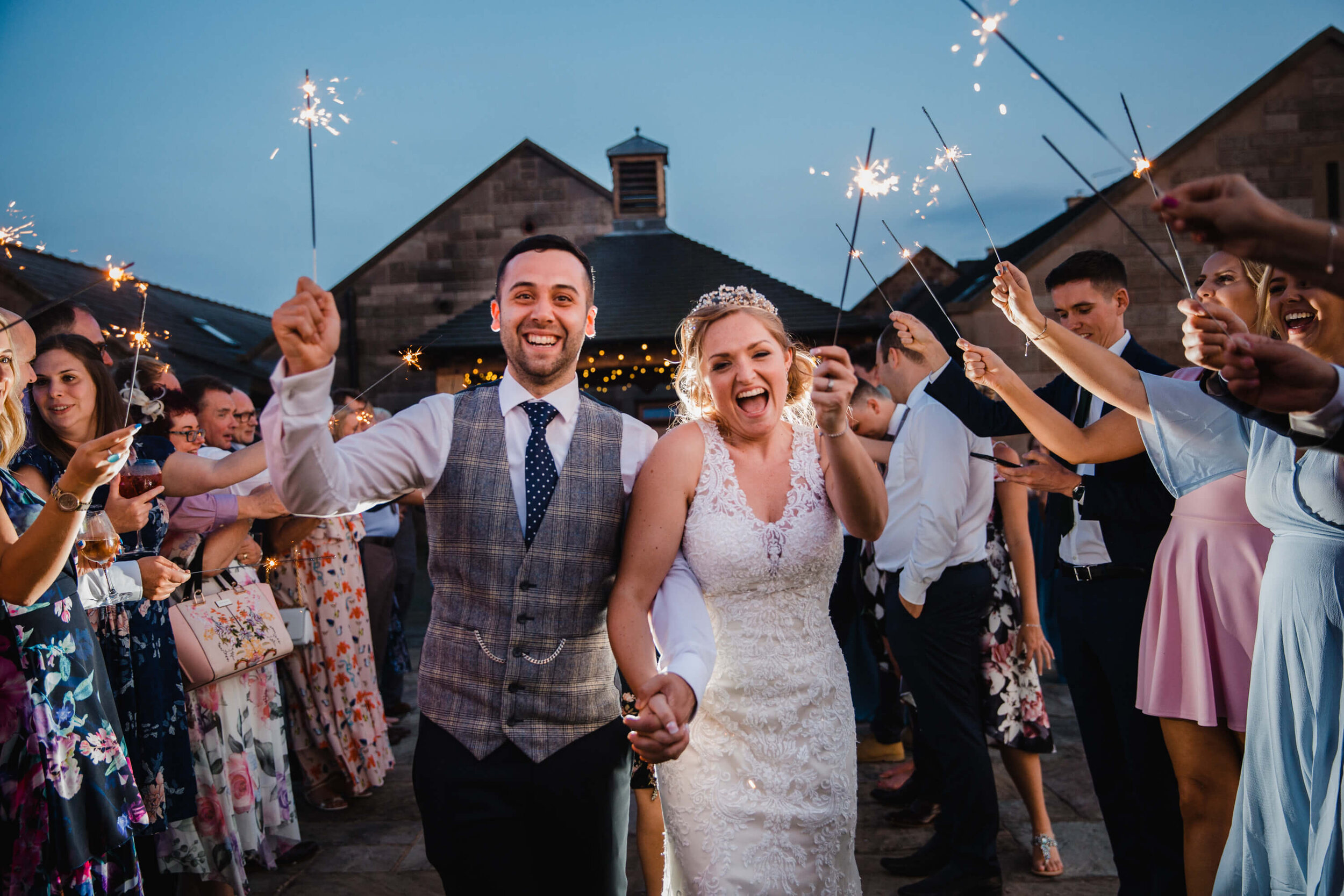 newlyweds enjoy sparkler exit on field surrounded by friends and family