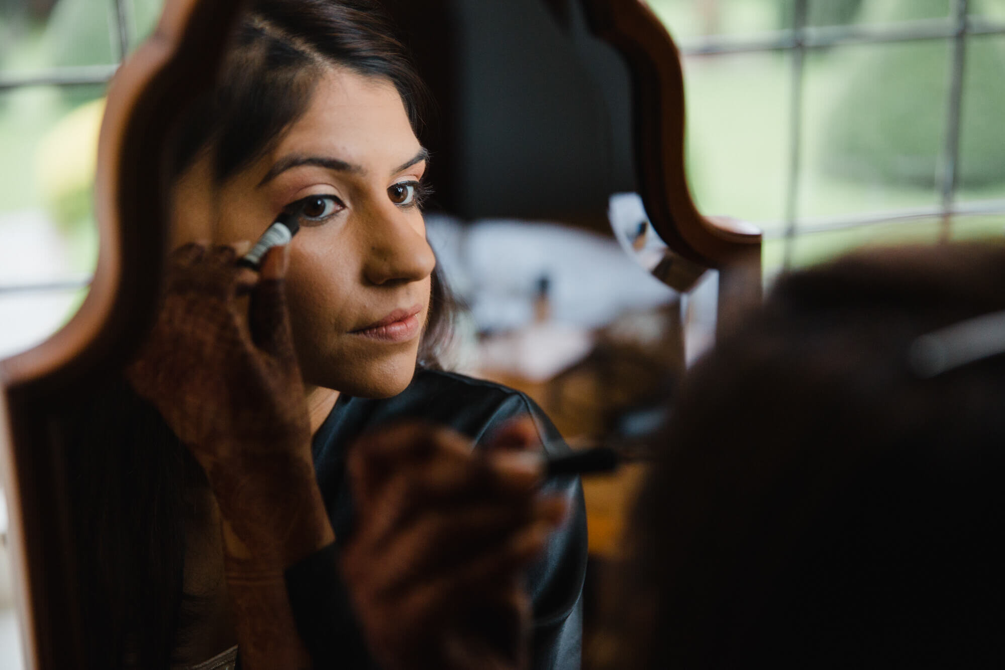 close up photograph of bride applying mascara in mirror