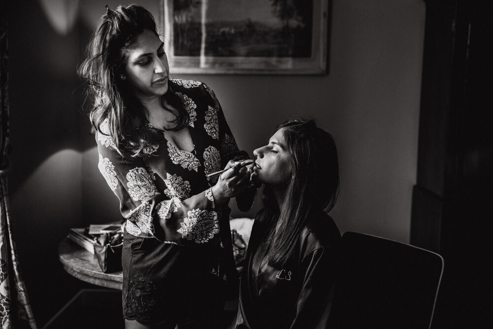black and white photograph of bride and sister having make up applied