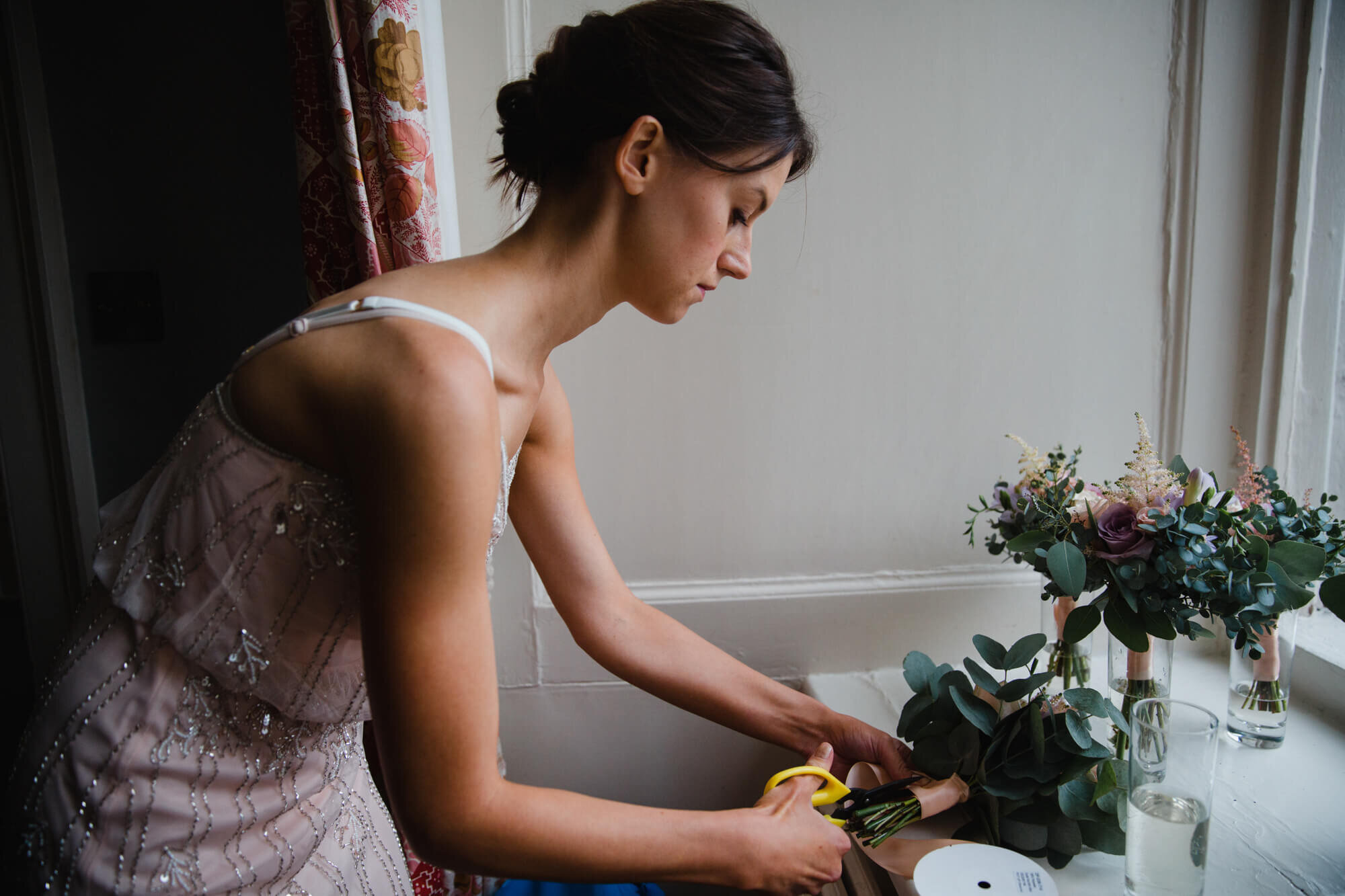 bridesmaid arranging floral bouquets by the window