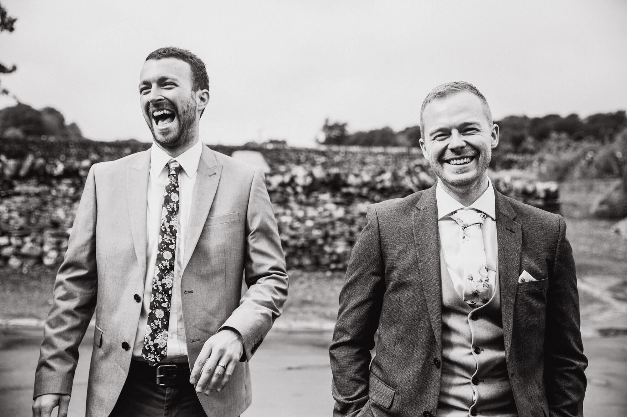 monochrome photograph of groomsmen laughing before service begins